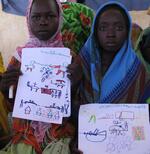 Darfuri girls in the Djabal Refugee Camp hold drawings of the violence they witnessed