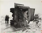 Man checking damage to oil truck after accident, I-84, West Hartford, February 8 or 10, 1970